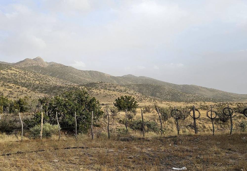 Fence line and adobe corner at the edge of the ranch under overcast sky