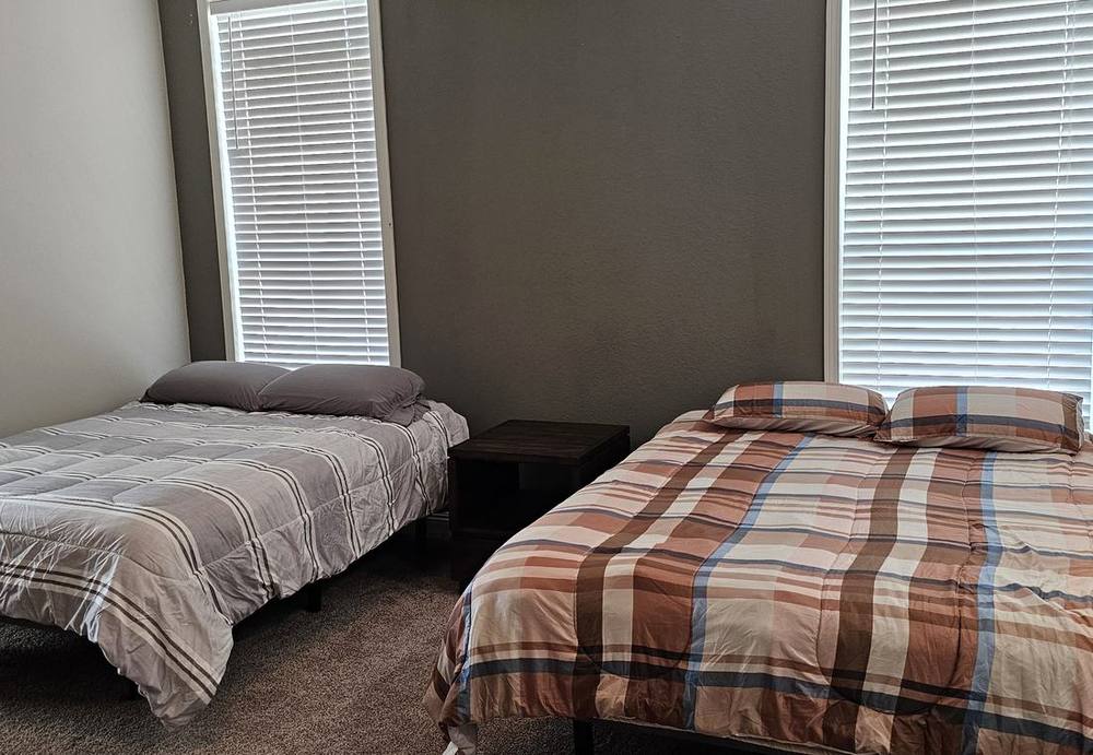 Lodge bedroom with two made beds and natural light through the blinds