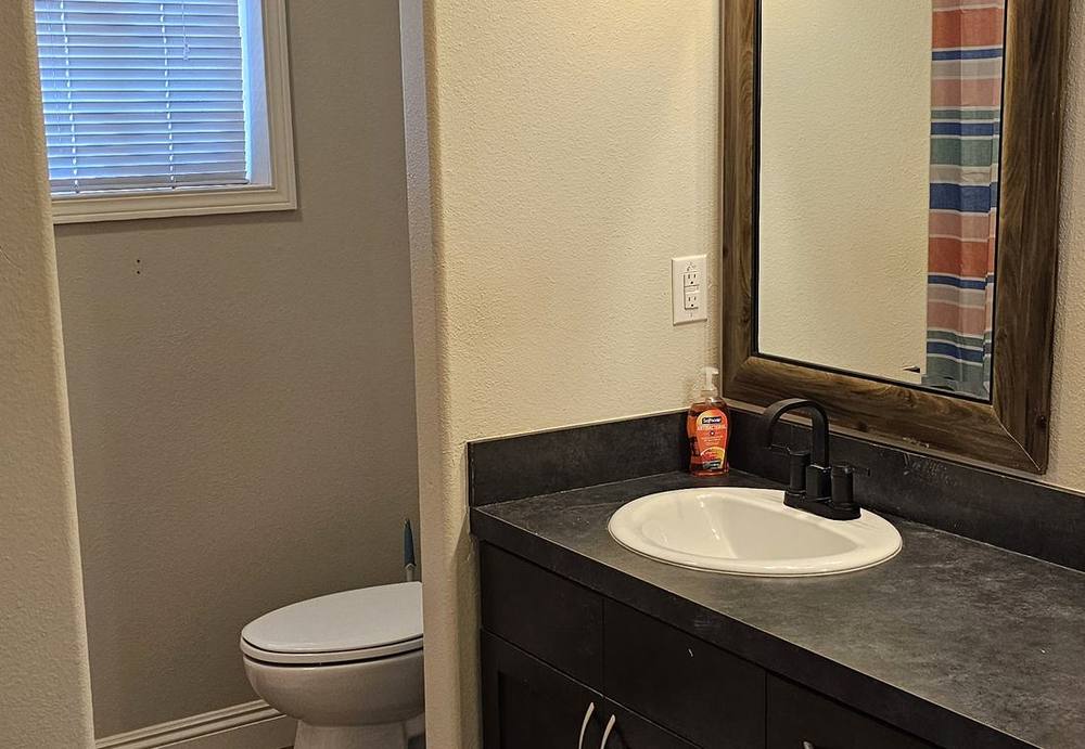 Lodge bathroom with a stone-top vanity and framed mirror