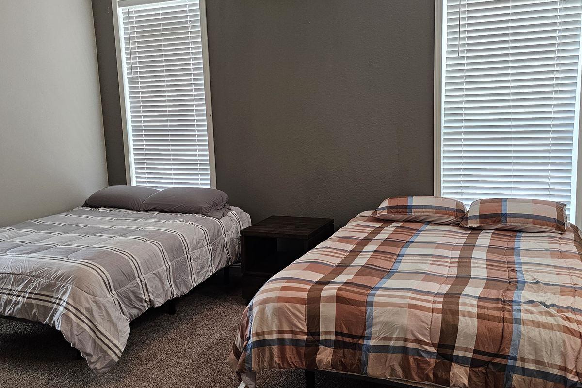 Lodge bedroom with two made beds and natural light through window blinds
